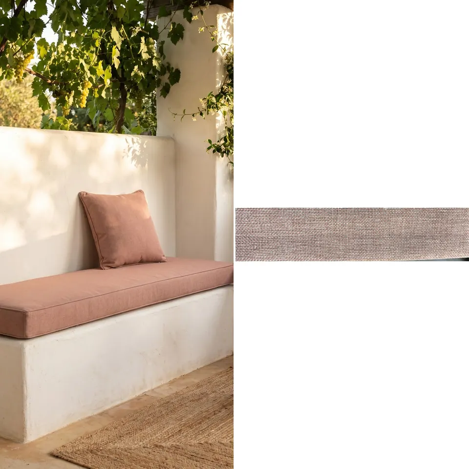 Dusty rose box cushion and matching square pillow on a white built-in masonry bench under a grapevine, with fabric strip