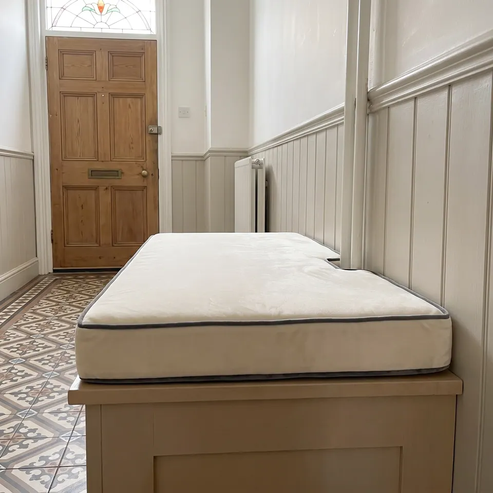 Cream velvet hallway bench cushion with graphite piping, notched for a pipe box above a Victorian tiled floor
