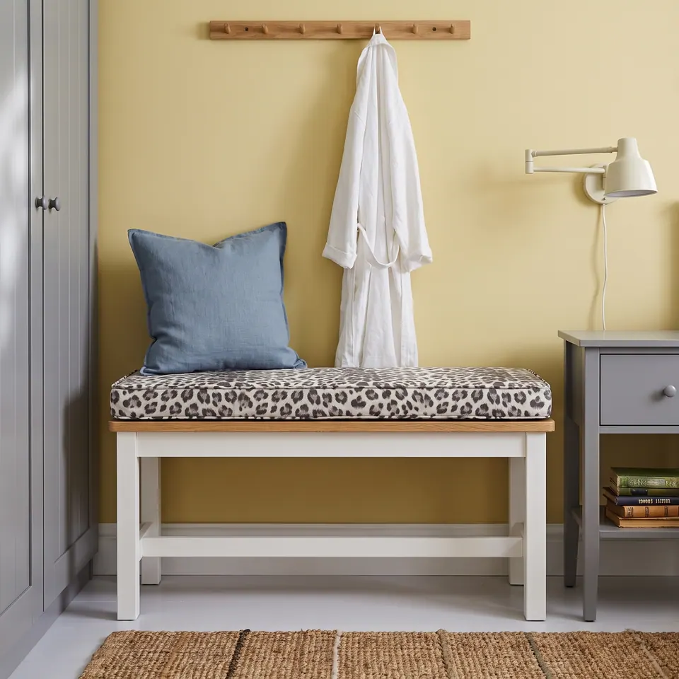 Gray snow-leopard print bench cushion on a white oak-topped bench against a butter-yellow wall with a blue linen pillow