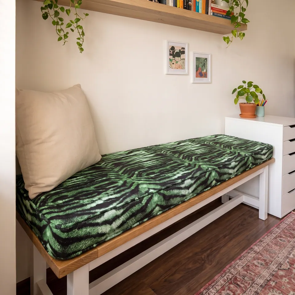 Angled view of a green tiger-stripe box cushion running along an oak-topped bench toward a white drawer unit