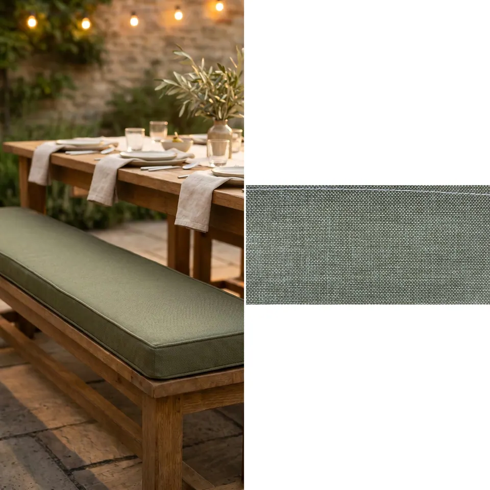 Olive green box cushion with self piping on a teak outdoor dining bench beside a table set with linen napkins at dusk