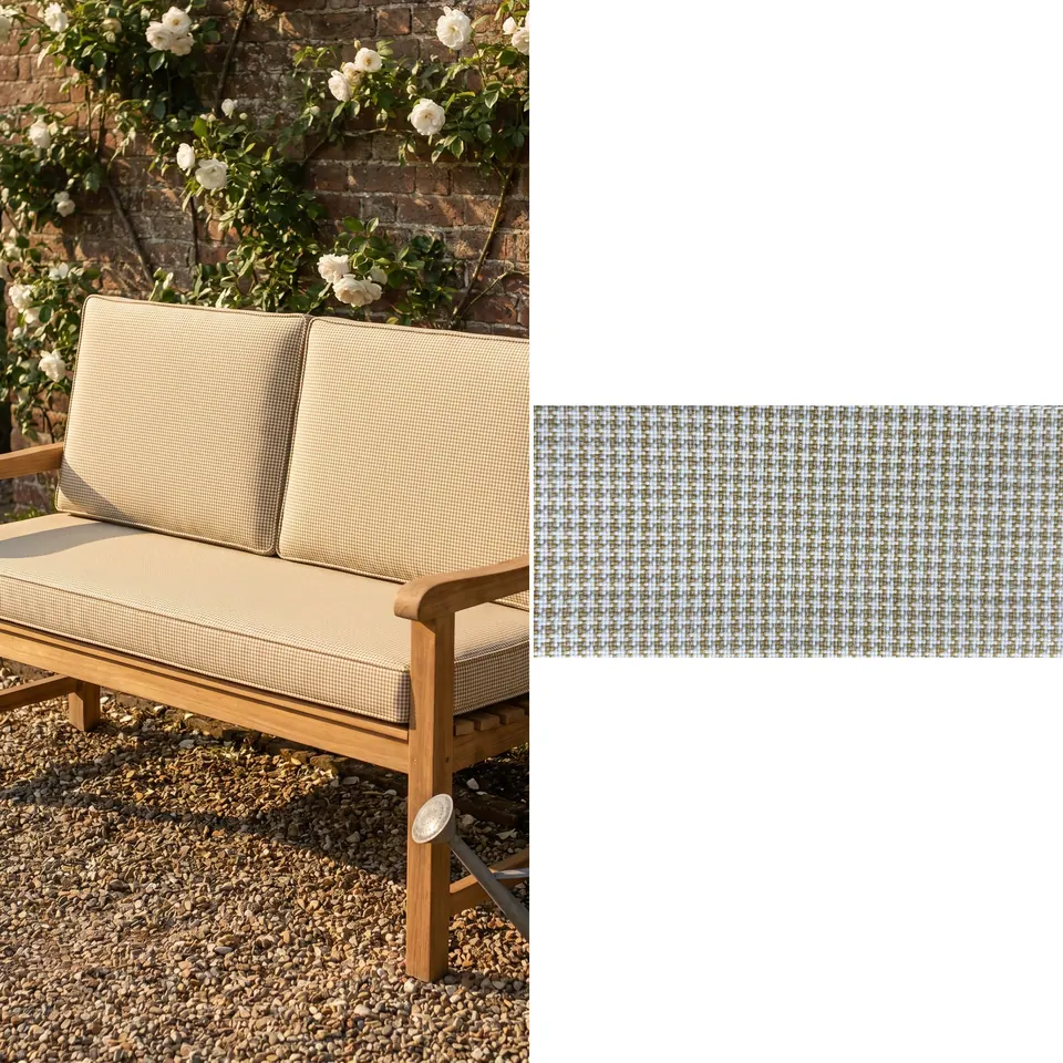 Sand beige micro-check seat and back cushions with self piping on a teak garden loveseat by a rose-covered brick wall