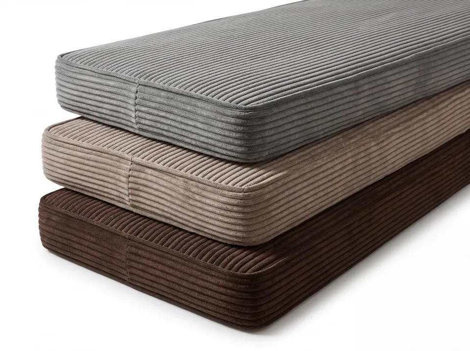 Stack of three long corduroy bench cushions in slate gray, taupe and chocolate brown with piped box edges on white