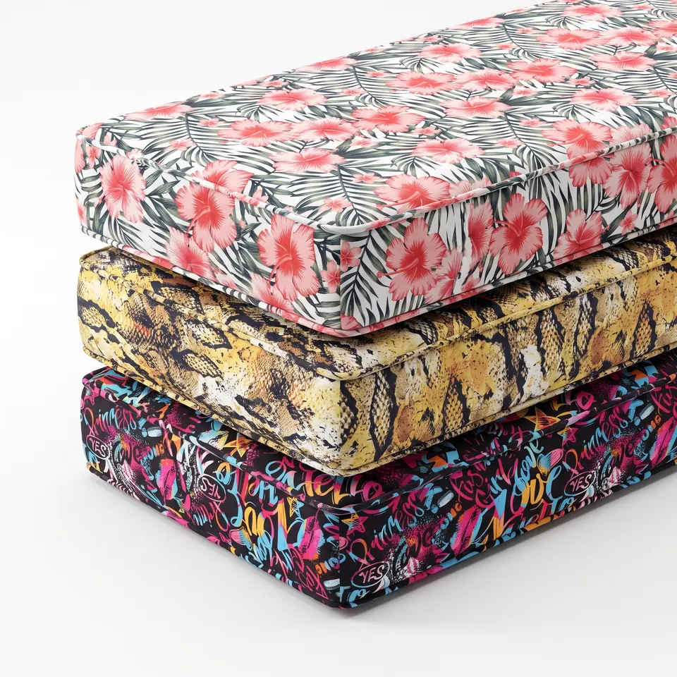 Three piped box cushions stacked on white: coral hibiscus on palm fronds, yellow python print and black graffiti script