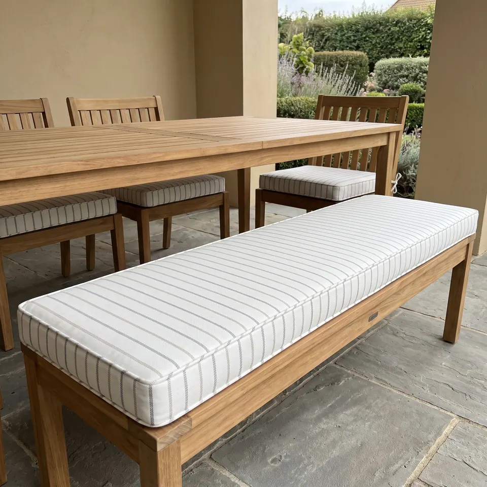 White box cushion with tan and gray pinstripes on a teak dining bench, matching chair pads at a teak table