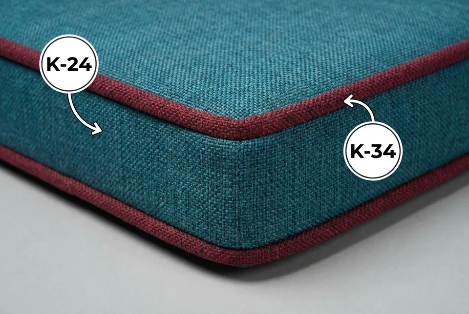 Close-up of a teal linen-weave box cushion corner with raspberry red piping, showing coarse basket-weave texture