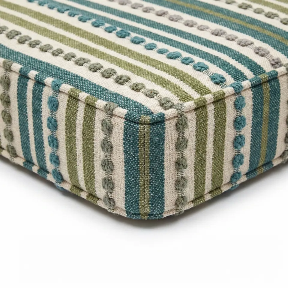 Overhead view of a teal and olive striped box cushion corner with gray and teal knots, showing deep boxing and self piping