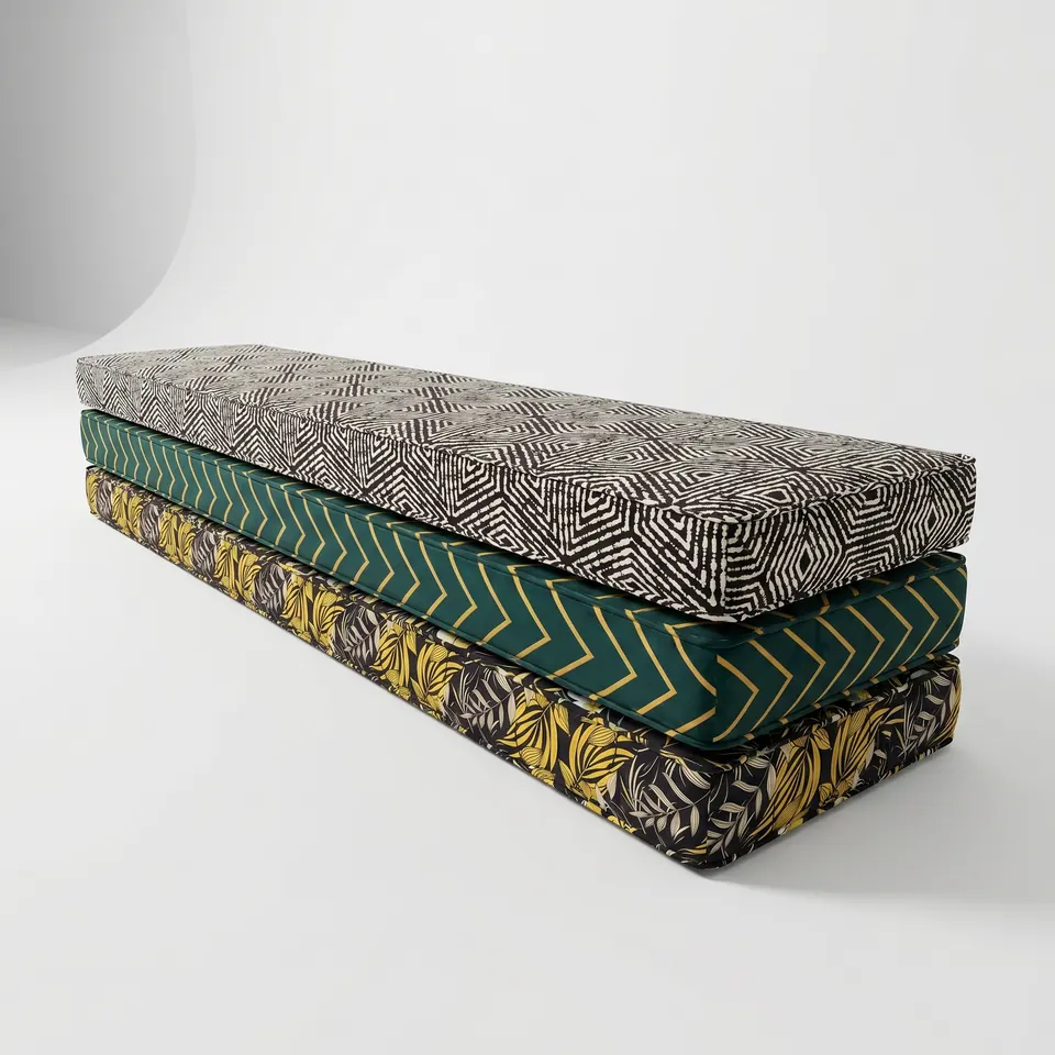 Three long box cushions stacked on white: black and white diamond print, emerald gold chevron and black mustard leaf print
