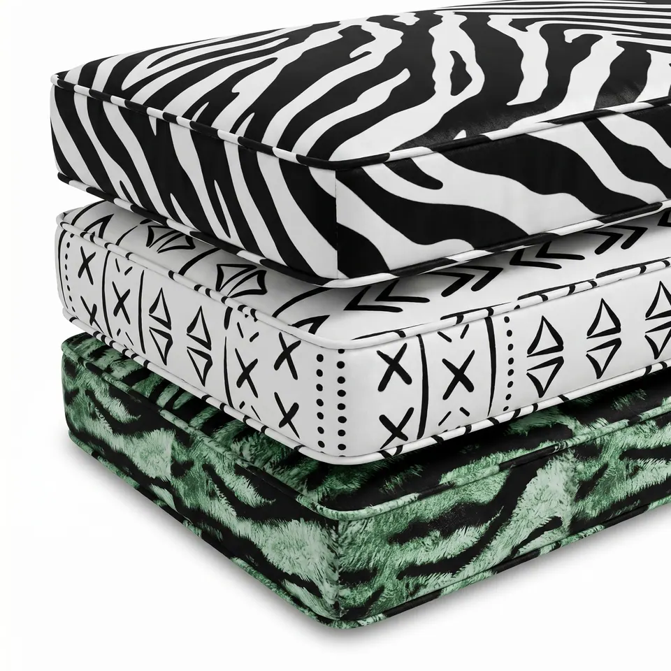 Three stacked box cushions in black and white zebra, white mudcloth and green tiger print fabric on a white background