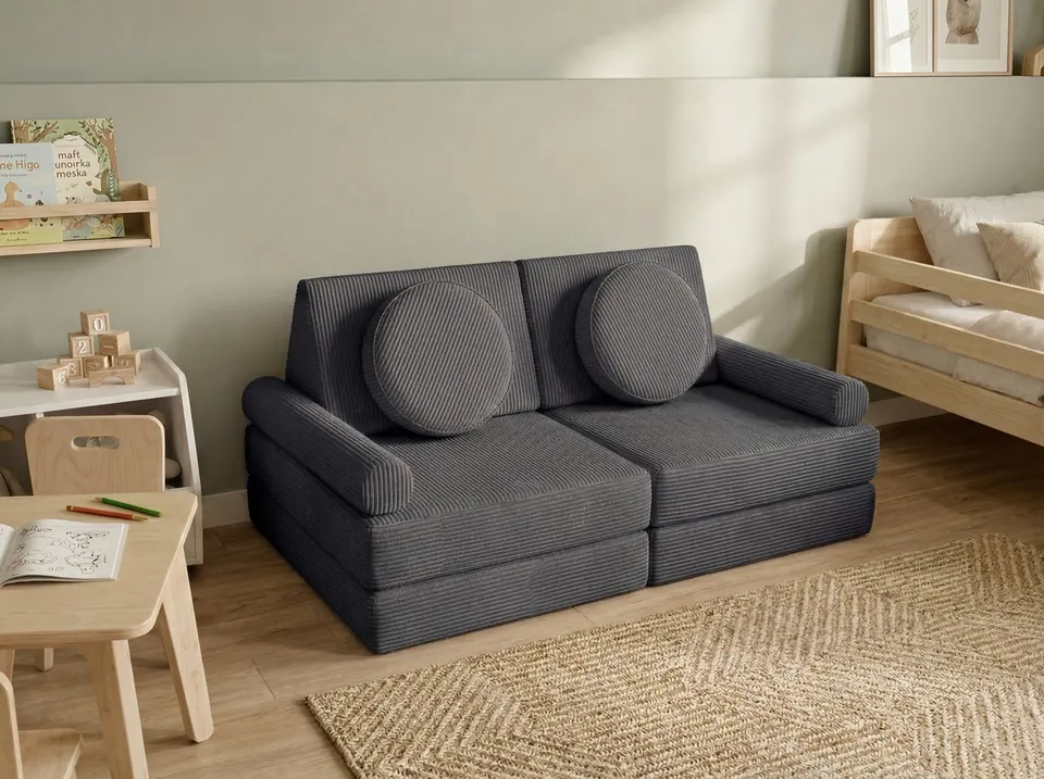 Charcoal gray corduroy modular kids sofa with two round pillows and bolster arms on a diamond-weave jute rug