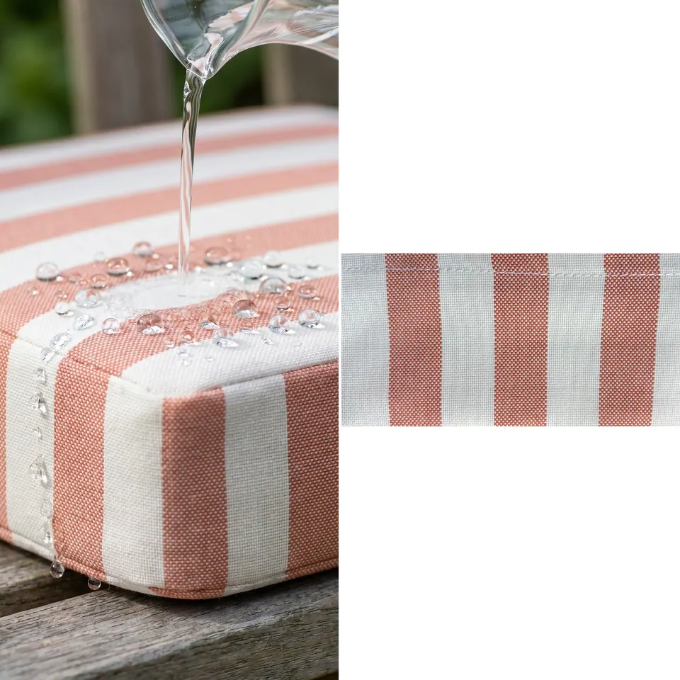 Water poured from a glass jug beading on a coral and white stripe outdoor box cushion and running off its side
