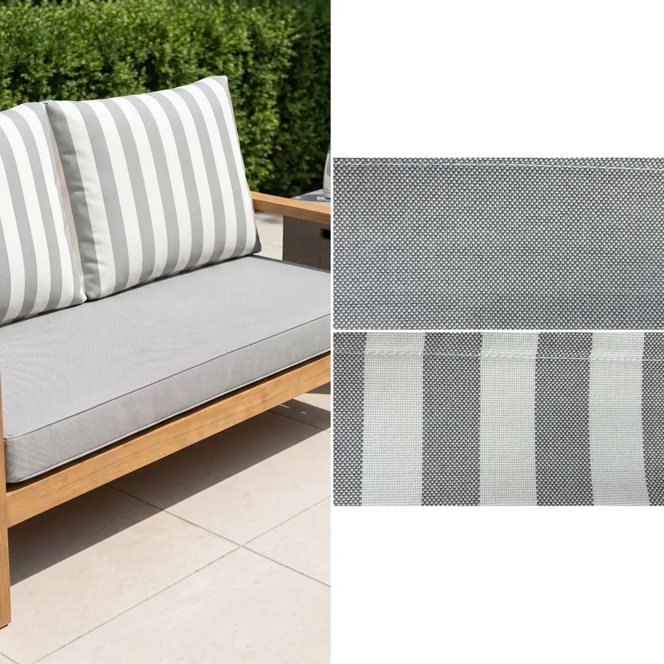 Dove gray piped seat cushion and two gray and white awning stripe back cushions on a teak garden loveseat by a hedge