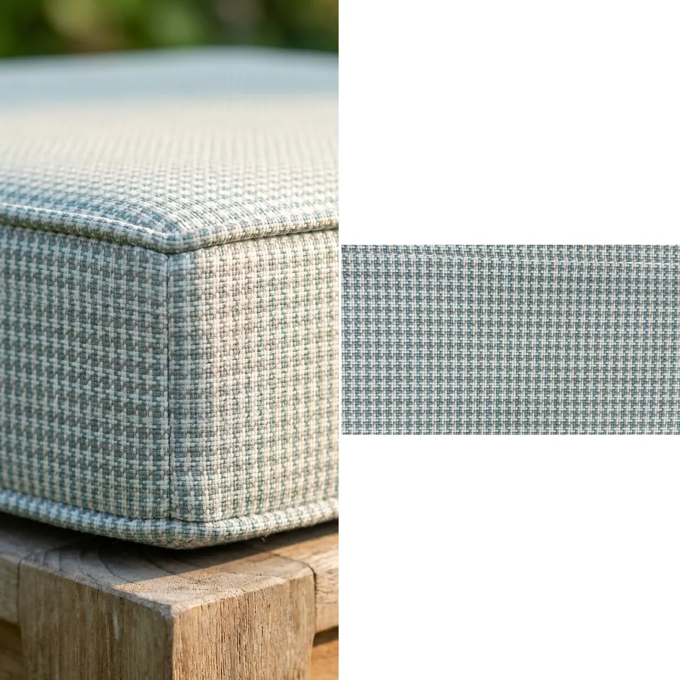 Close view of a sage-gray and ivory micro-houndstooth box cushion corner with self piping on a weathered teak frame