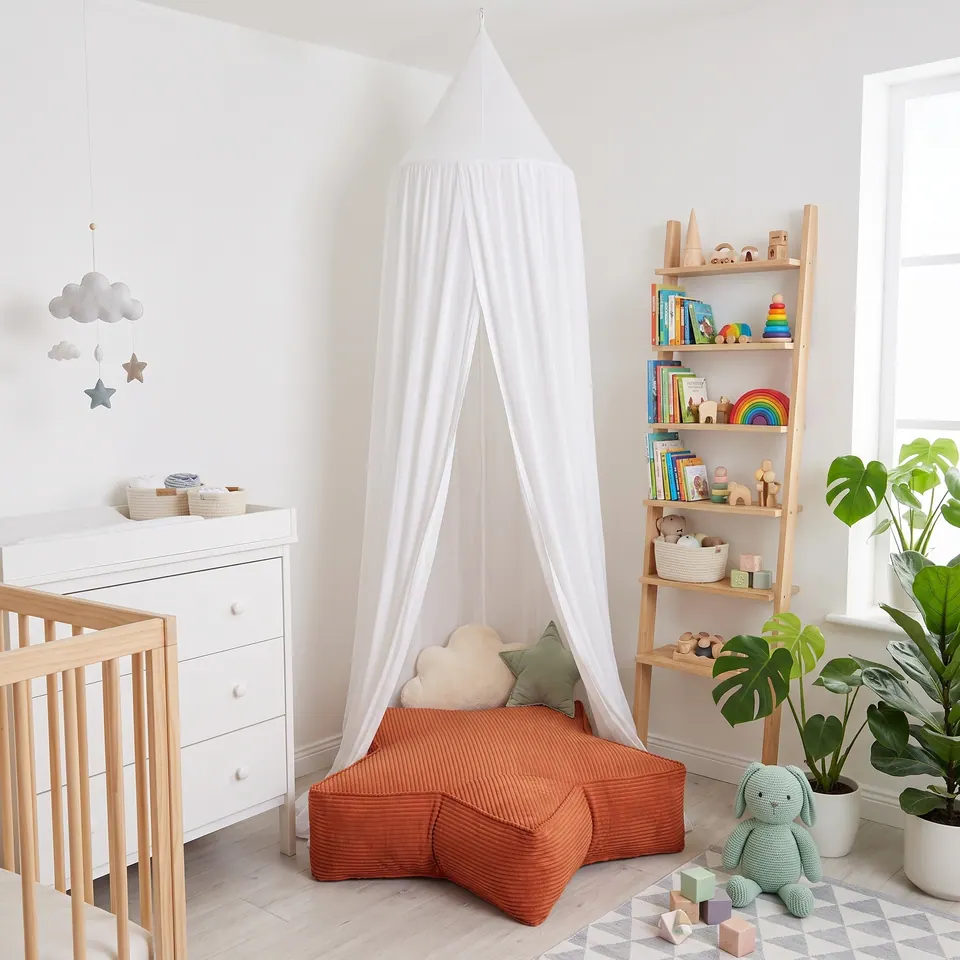 Rust orange corduroy star floor pouf with sage star and cream cloud pillows under a white canopy in a bright nursery