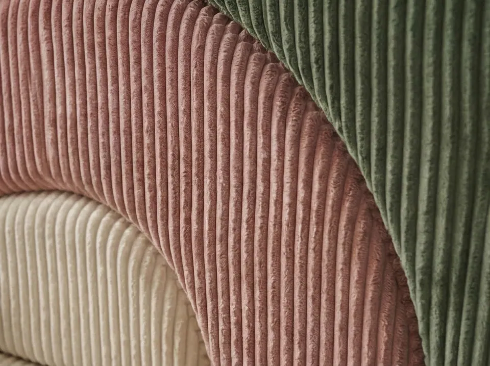 Close-up of wide-wale corduroy in blush pink, sage green and cream wrapped around curved foam arches