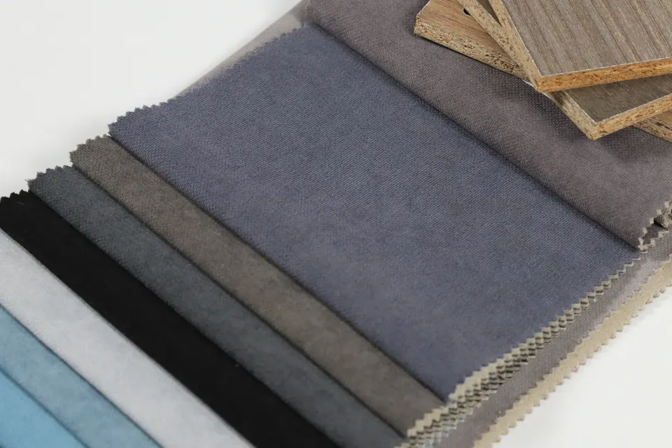 Slate blue-gray linen-look fabric swatch over taupe, black and sky blue strips on a white table