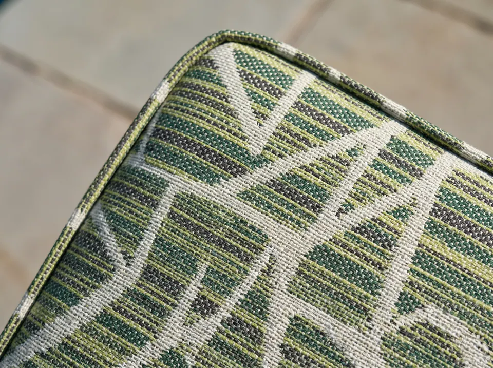 Macro of a piped corner on a green, lime, charcoal and ivory geometric woven outdoor cushion fabric