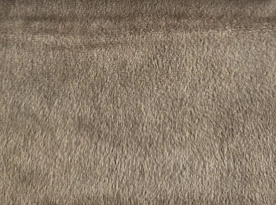 Latte brown velvet swatch with pile brushed one way, pale fiber tips and a shadowed fold along the upper edge