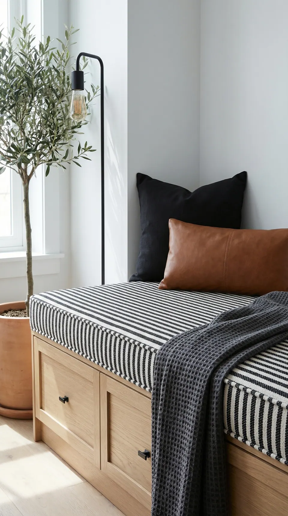 Pinned: Black and white striped window seat cushion on oak drawers with black and cognac leather pillows, waffle throw and olive tree