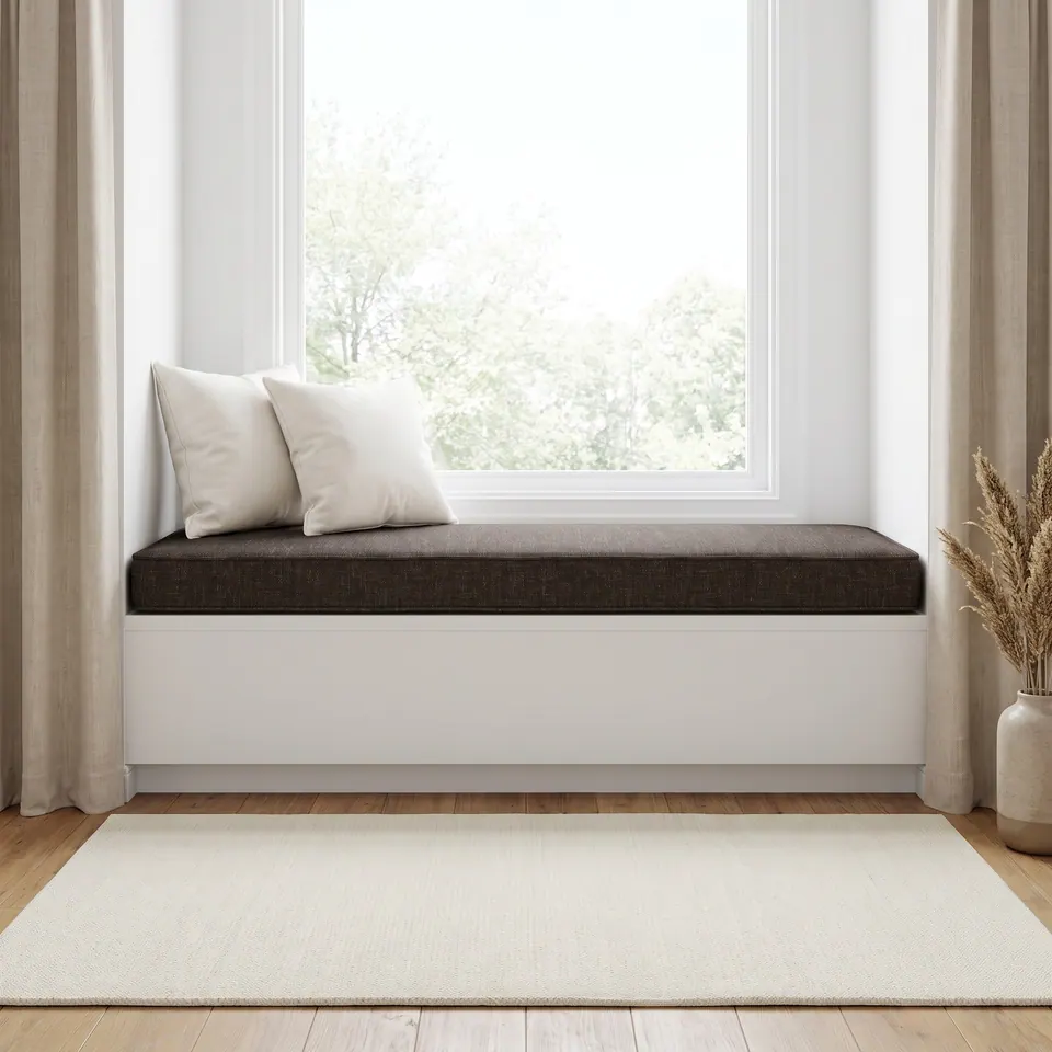 Chocolate brown tweed-look window seat cushion, self piped, two ivory pillows, framed by linen curtains and a leafy view
