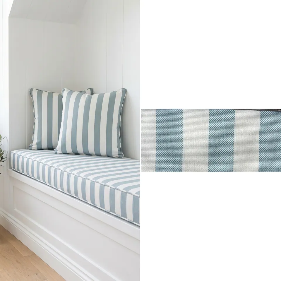 Sea-blue and white awning stripe window seat cushion with two matching piped pillows in a white paneled nook, fabric strip